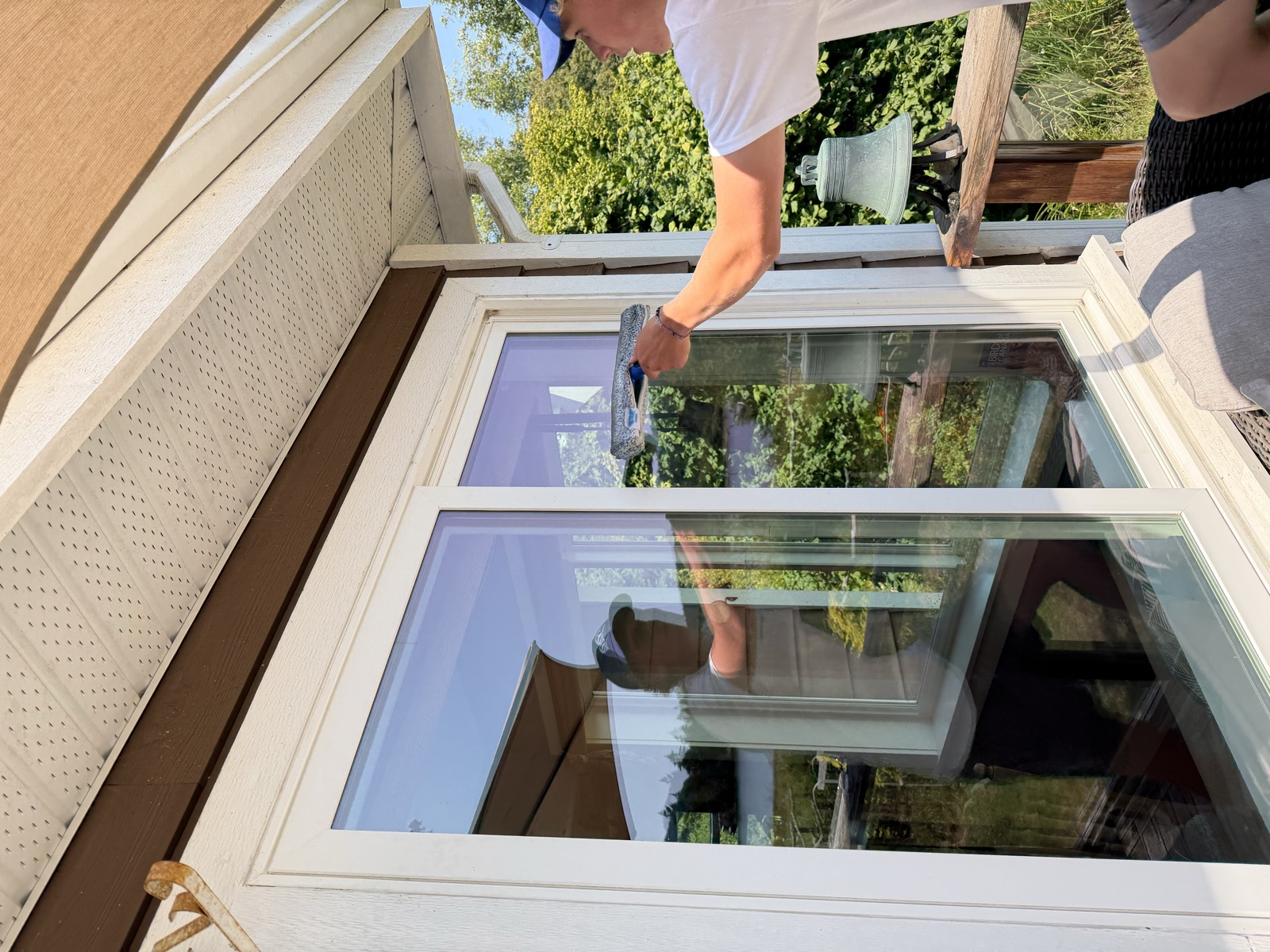 Zephyr Beckers, owner of Pacific Windows, squeegeeing a window at a lakeside home in Sooke BC